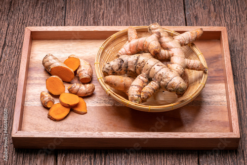 Turmeric root and sliced in wooden plate, Table top view Curcuma Longa Linn or rhizome root on a wooden table background.