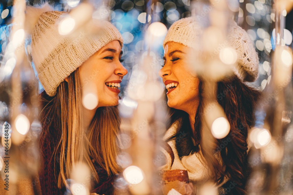 Happy women friends having fun, enjoying moments together in christmas decorated background. - obrazy, fototapety, plakaty 