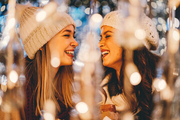 Happy women friends having fun, enjoying moments together in christmas decorated background.