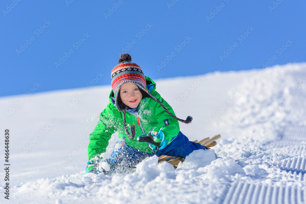 kleiner Junge beim Schlittenfahren im Winter.
