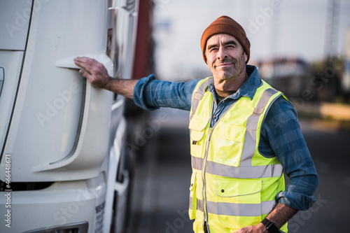 Smiling male driver standing by truck photo