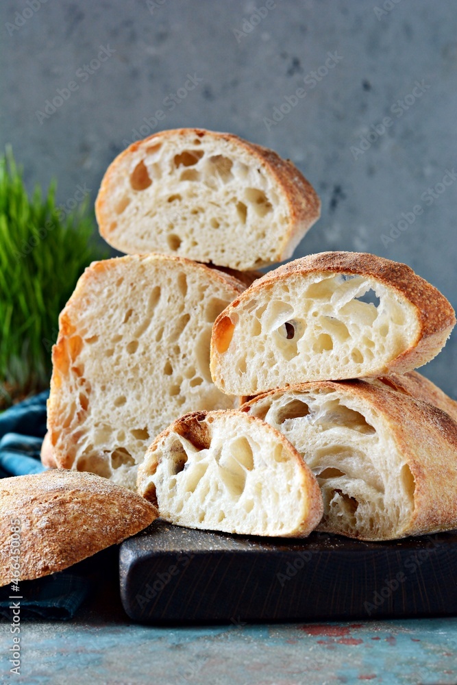 Fresh Italian ciabatta with crispy crust, moist crumb and large pores on a light blue background. Homemade sourdough bread (yeast-free). Food balance. Fresh Italian ciabatta with crispy crust, moist crumb and large pores on a light blue background. Homemade sourdough bread (yeast-free). Food balance.