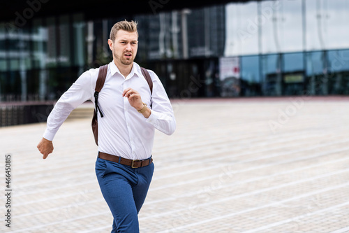 Young businessman with backpack running on footpath
