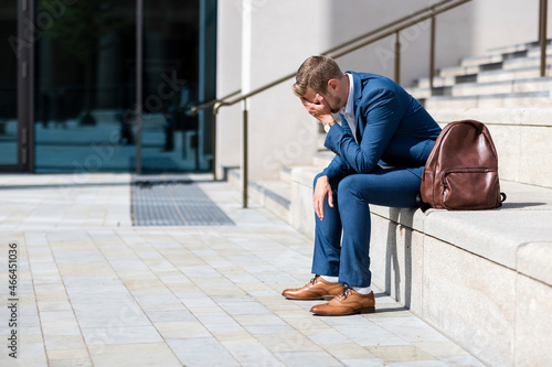 Worried businessman with head in hand sitting on steps photo