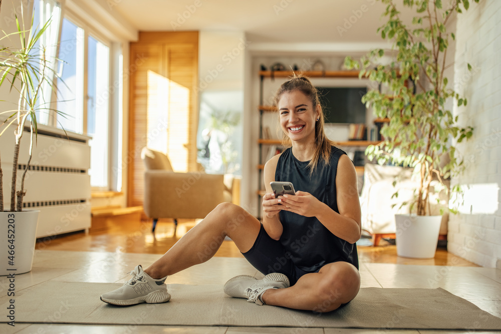 Shot of caucasian woman, using a phone during training Shot of caucasian woman, using a phone during training