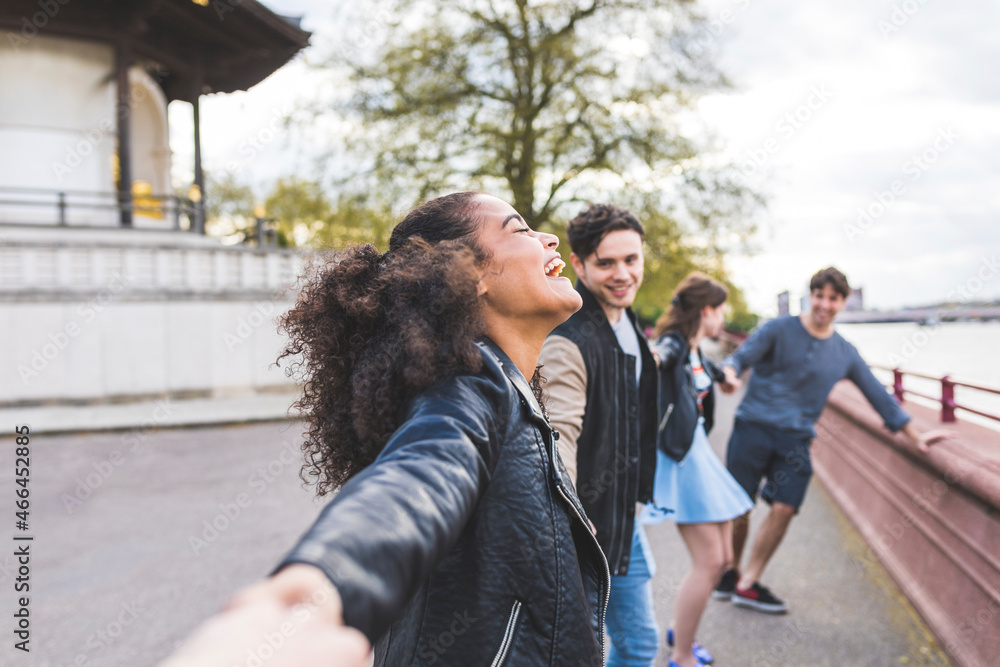 Laughing woman holding hands of friends in park Laughing woman holding hands of friends in park