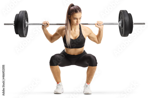 Fit young woman bodybuilder kneeling with heavy weights