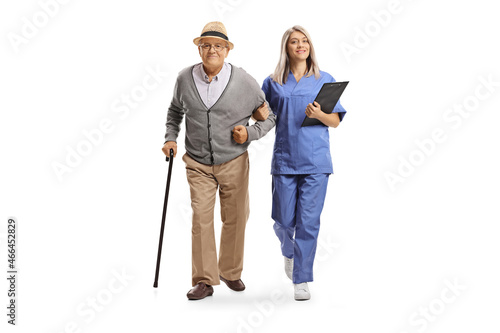 Full length portrait of a young female nurse in a blue uniform helping an elderly man