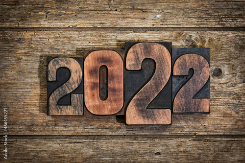 Year 2022 written with vintage letterpress printing blocks on rustic wooden background