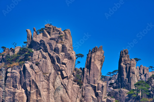 High granite mountains with green trees, blue sky and white clouds. Landscape of Mount Huangshan (Yellow Mountain). UNESCO World Heritage Site. Anhui Province, China.