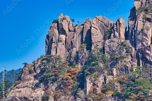 High granite mountains with green trees, blue sky and white clouds. Landscape of Mount Huangshan (Yellow Mountain). UNESCO World Heritage Site. Anhui Province, China.