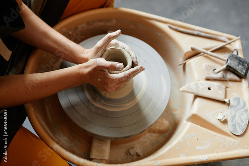 Top view close up of young woman working on pottery wheel together in handmade ceramics workshop, copy space