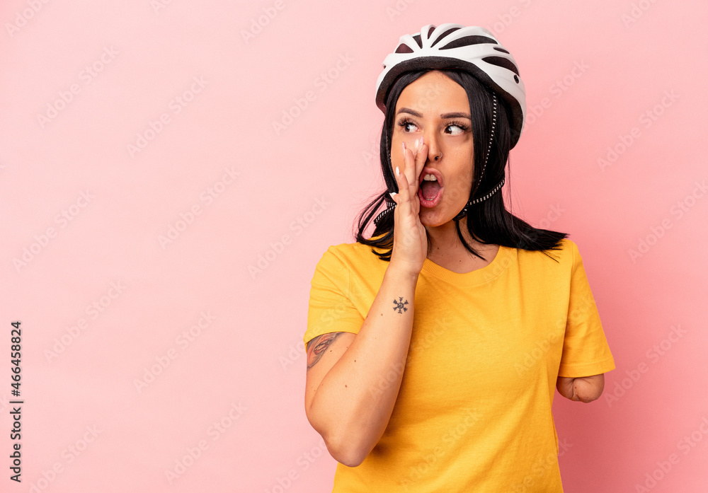 Young caucasian woman with one arm wearing a bike helmet isolated on pink background is saying a secret hot braking news and looking aside Young caucasian woman with one arm wearing a bike helmet isolated on pink background is saying a secret hot braking news and looking aside
