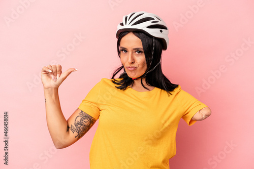 Young caucasian woman with one arm wearing a bike helmet isolated on pink background feels proud and self confident, example to follow. © Asier