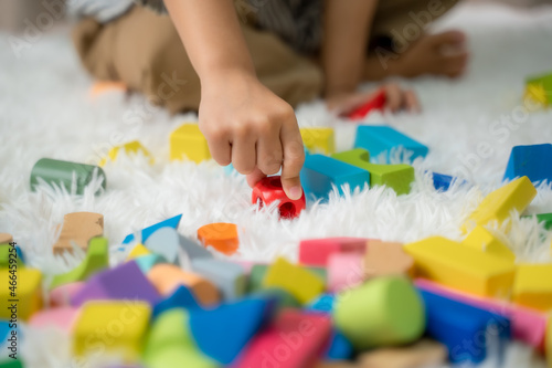 Little siblings playing colorful wooden blocks in home,Sitting on floor, Concept for funny activity of young kids in free time.