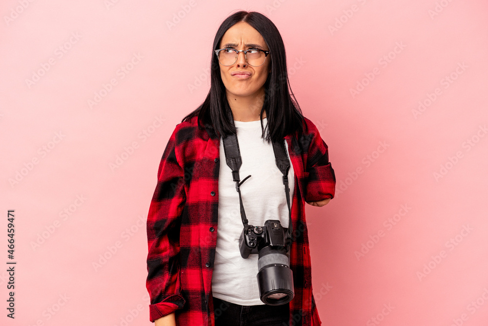 Young caucasian photography woman with one arm isolated on pink background confused, feels doubtful and unsure. Young caucasian photography woman with one arm isolated on pink background confused, feels doubtful and unsure.
