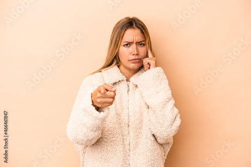 Young caucasian woman isolated on beige background pointing temple with finger, thinking, focused on a task.