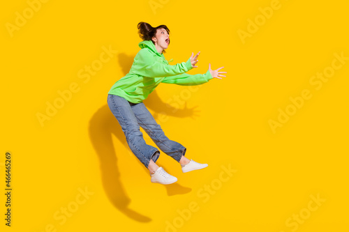 Full length body size view of lovely amazed girl jumping catching copy space isolated over bright yellow color background