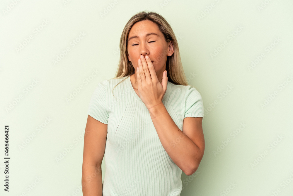 Young caucasian woman isolated on green background yawning showing a tired gesture covering mouth with hand. Young caucasian woman isolated on green background yawning showing a tired gesture covering mouth with hand.