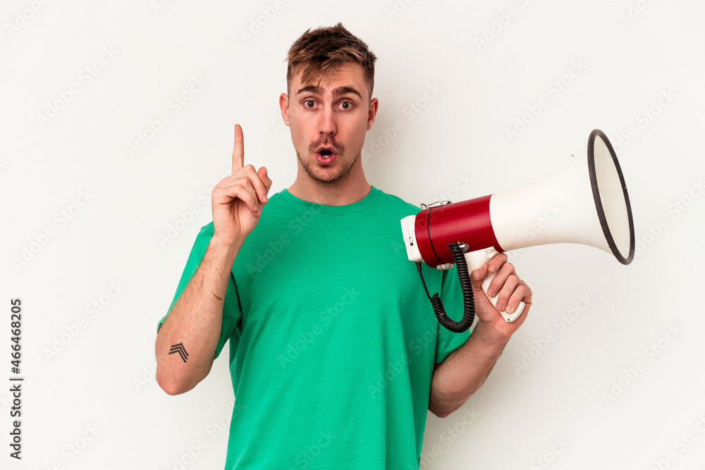 Young caucasian man holding megaphone isolated on white background having some great idea, concept of creativity. Young caucasian man holding megaphone isolated on white background having some great idea, concept of creativity.
