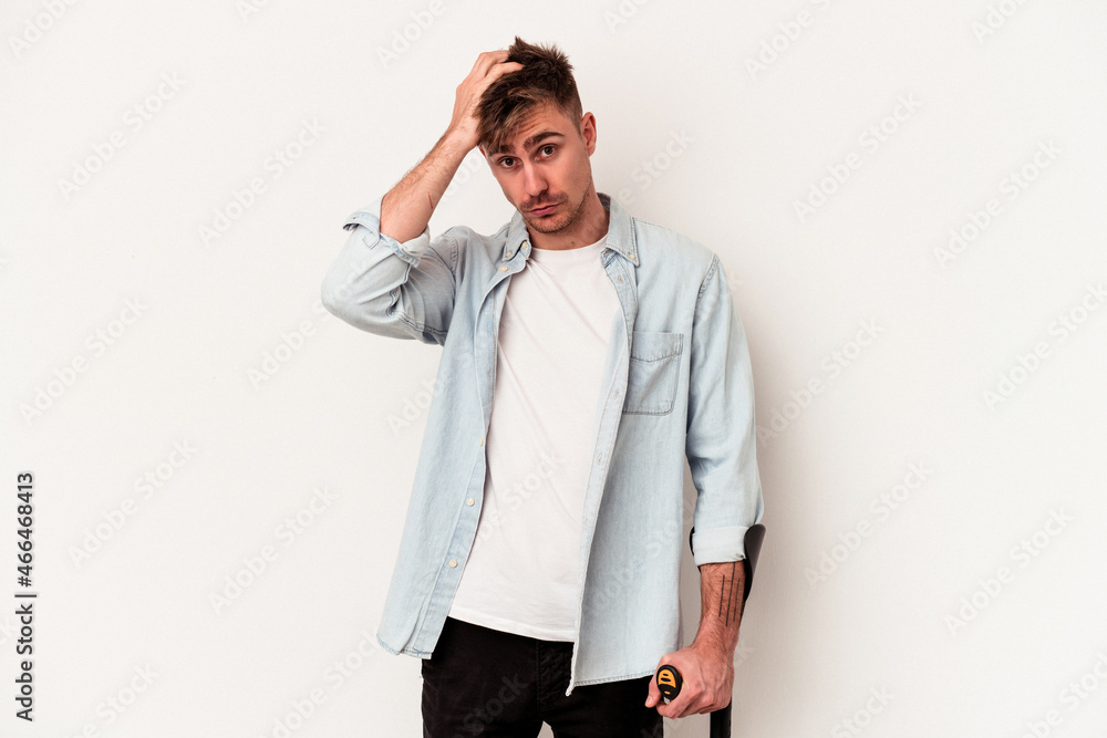 Young caucasian man holding crutch isolated on white background being shocked, she has remembered important meeting. Young caucasian man holding crutch isolated on white background being shocked, she has remembered important meeting.