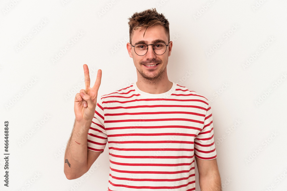 Young caucasian man isolated on white background joyful and carefree showing a peace symbol with fingers. Young caucasian man isolated on white background joyful and carefree showing a peace symbol with fingers.