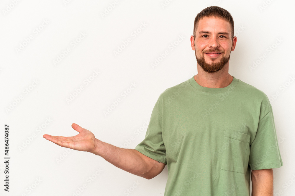 Young caucasian man with diastema isolated on white background showing a copy space on a palm and holding another hand on waist. Young caucasian man with diastema isolated on white background showing a copy space on a palm and holding another hand on waist.