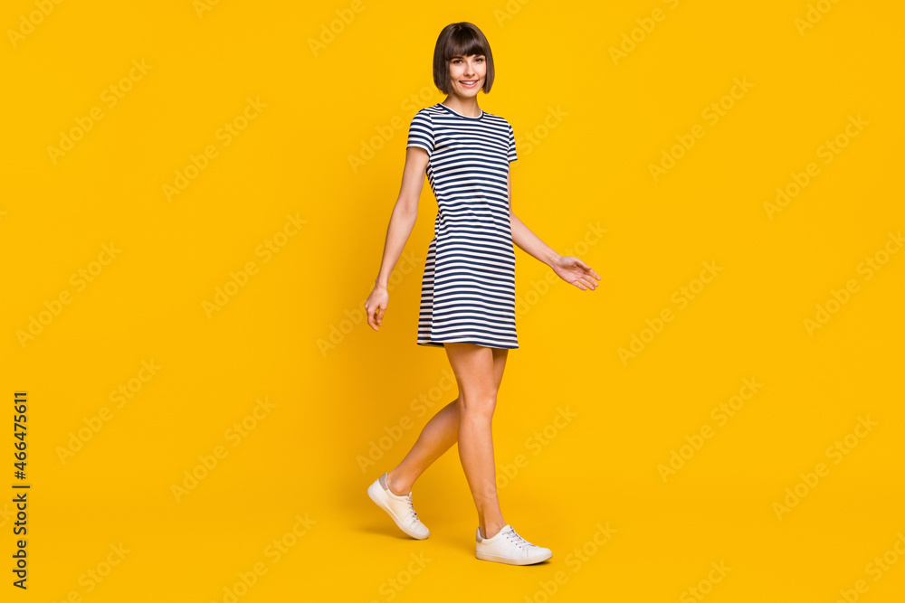 Full size profile photo of nice brunette young lady go wear striped dress sneakers isolated on yellow background Full size profile photo of nice brunette young lady go wear striped dress sneakers isolated on yellow background