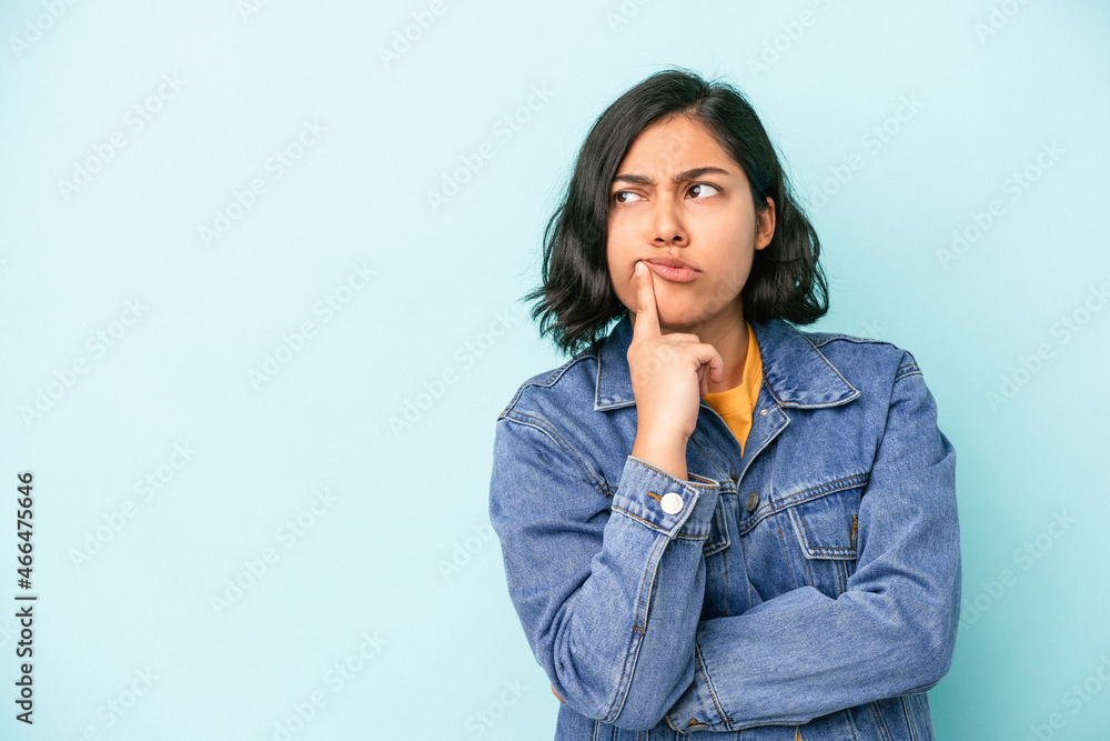 Young latin woman isolated on blue background looking sideways with doubtful and skeptical expression. Young latin woman isolated on blue background looking sideways with doubtful and skeptical expression.