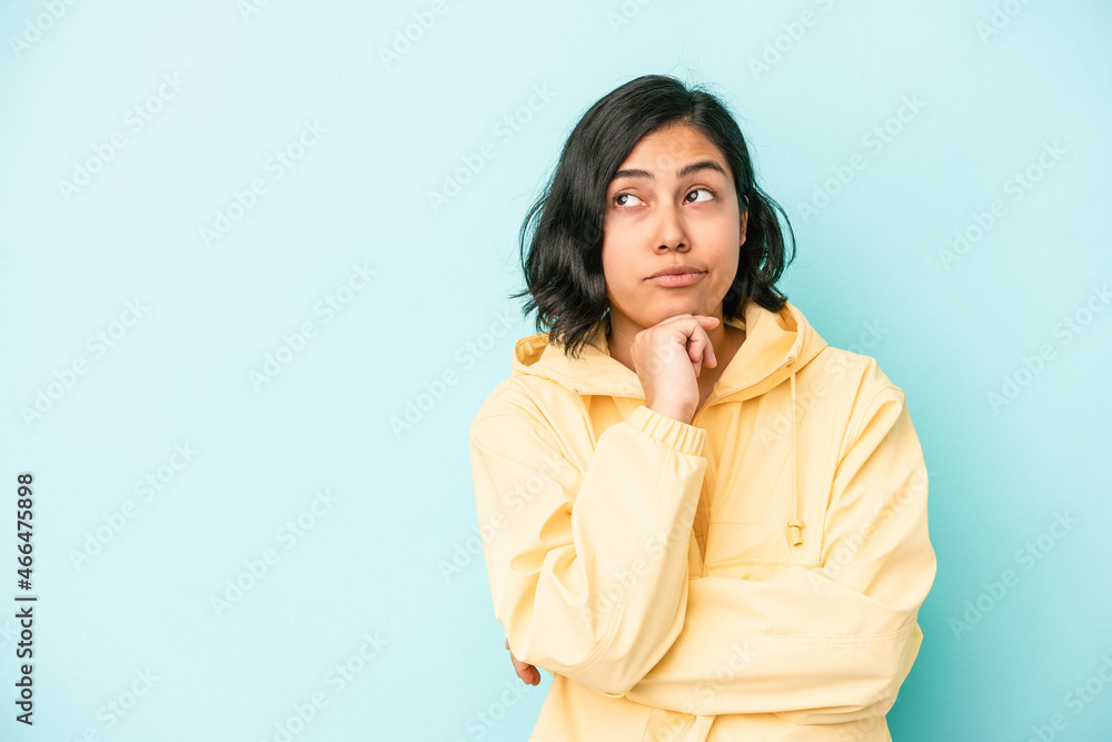 Young latin woman isolated on blue background looking sideways with doubtful and skeptical expression. Young latin woman isolated on blue background looking sideways with doubtful and skeptical expression.