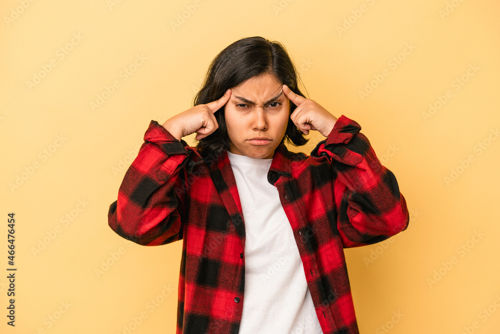 Young latin woman isolated on yellow background focused on a task, keeping forefingers pointing head. Young latin woman isolated on yellow background focused on a task, keeping forefingers pointing head.