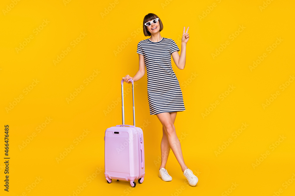 Full lenght photo of cool brunette young lady stand show v-sign with bag wear dress sneakers eyewear isolated on yellow background Full lenght photo of cool brunette young lady stand show v-sign with bag wear dress sneakers eyewear isolated on yellow background