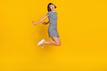 Full length photo of nice brunette millennial lady jump wear dress sneakers isolated on yellow background