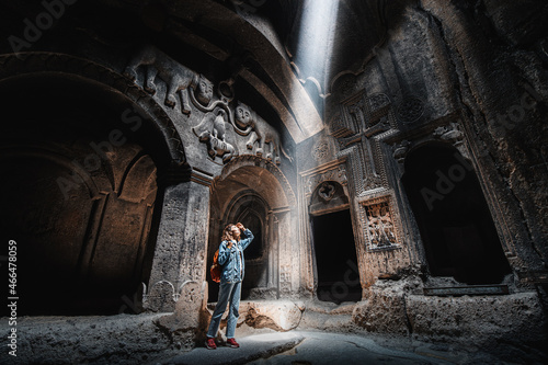 Fotografia Woman tourist explores the mystical interior of the main hall of the Armenian Geghard Monastery