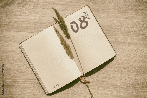 july 8. 8th day of month, calendar date.Blank pages of notebook are beige, with dried spikelets. Concept of day of year, time planner, summer month photo