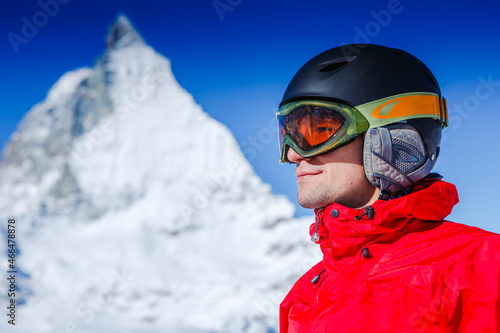 Happy man snowboarder posing with mountain landscape