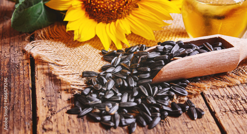 Sunflower seeds and oil bottle on old wooden background. Selective focus.