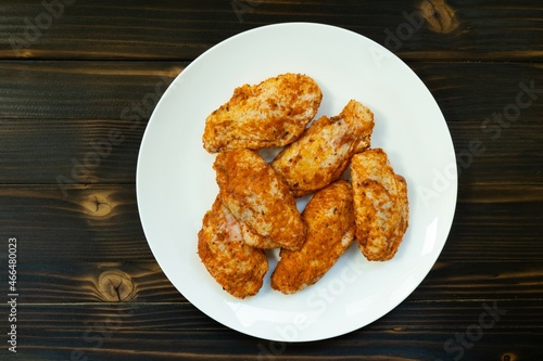 Raw chicken in white plate on wooden table.