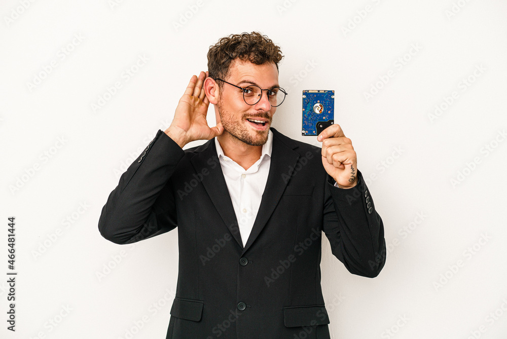 Young caucasian computerized holding HDD isolated on white background trying to listening a gossip. Young caucasian computerized holding HDD isolated on white background trying to listening a gossip.