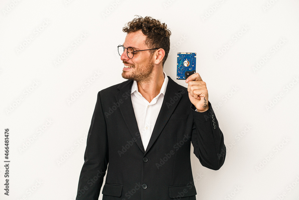 Young caucasian computerized holding HDD isolated on white background looks aside smiling, cheerful and pleasant. Young caucasian computerized holding HDD isolated on white background looks aside smiling, cheerful and pleasant.