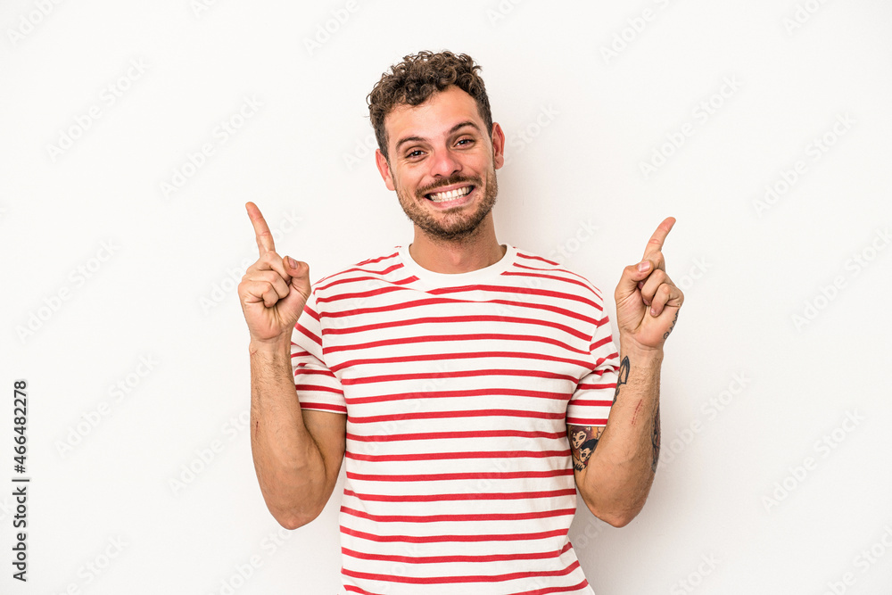 Young caucasian man isolated on white background indicates with both fore fingers up showing a blank space. Young caucasian man isolated on white background indicates with both fore fingers up showing a blank space.