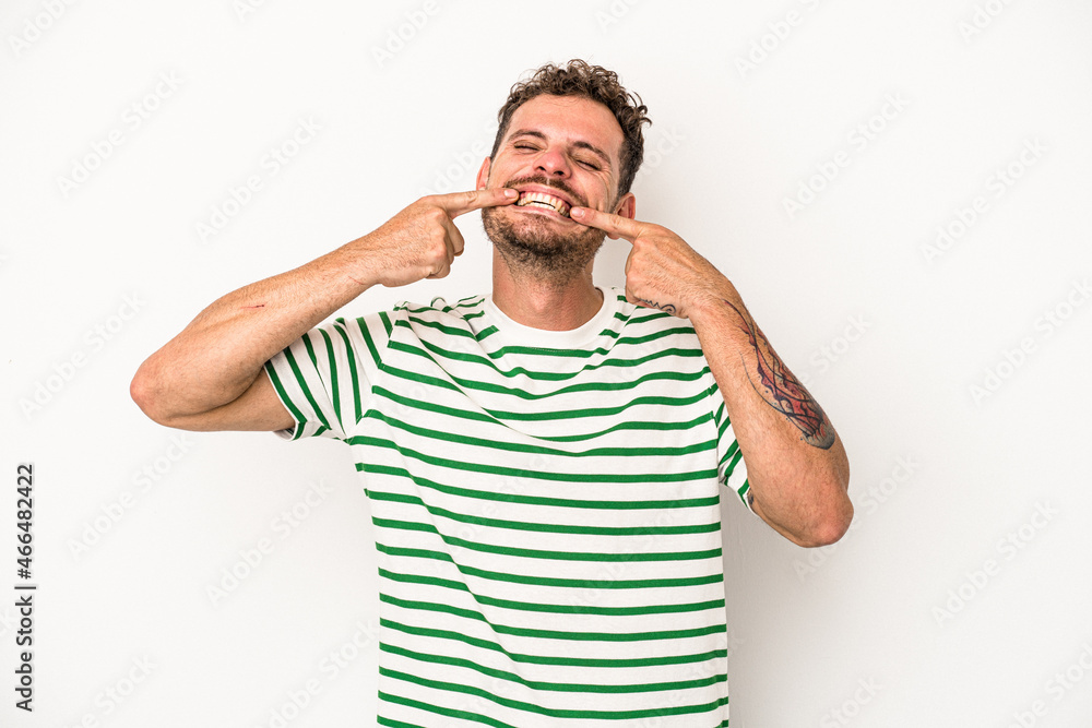 Young caucasian man isolated on white background smiles, pointing fingers at mouth. Young caucasian man isolated on white background smiles, pointing fingers at mouth.