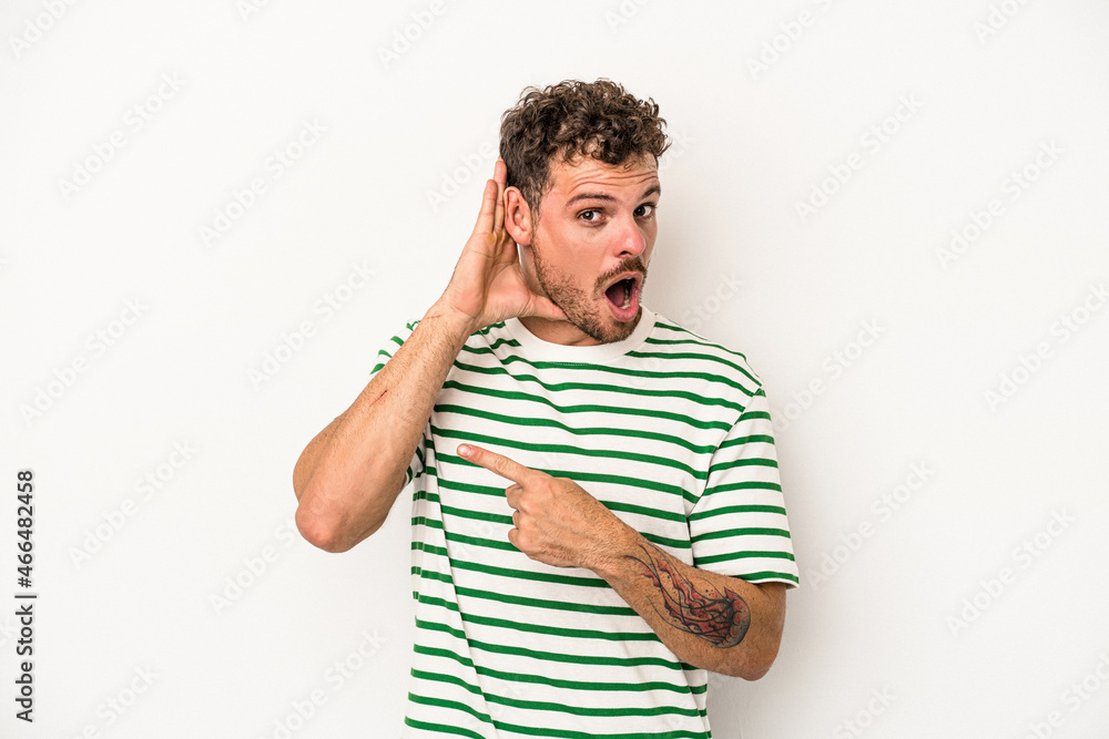 Fototapeta premium Young caucasian man isolated on white background trying to listening a gossip.