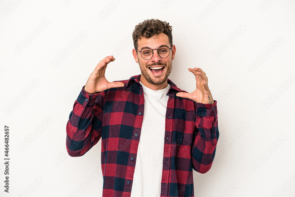 Naklejka premium Young caucasian man isolated on white background holding something with palms, offering to camera.