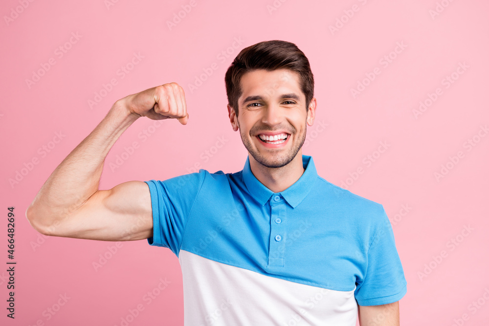 Portrait of attractive strong cheerful brunette guy demonstrating muscles isolated over pink pastel color background Portrait of attractive strong cheerful brunette guy demonstrating muscles isolated over pink pastel color background