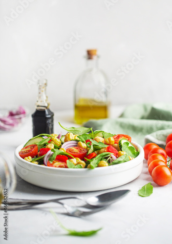 Vegetarian chickpea beans salad prepared with tomatoes and cucumber on a white background