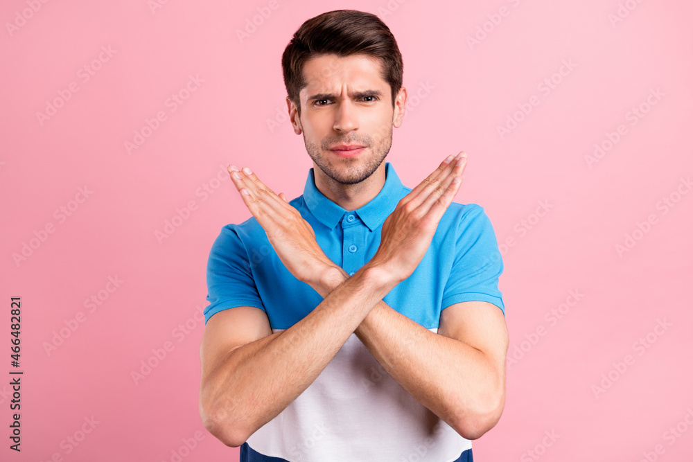 Photo of young serious confident guy showing stop no gesture cross hands deny isolated on pink color background Photo of young serious confident guy showing stop no gesture cross hands deny isolated on pink color background