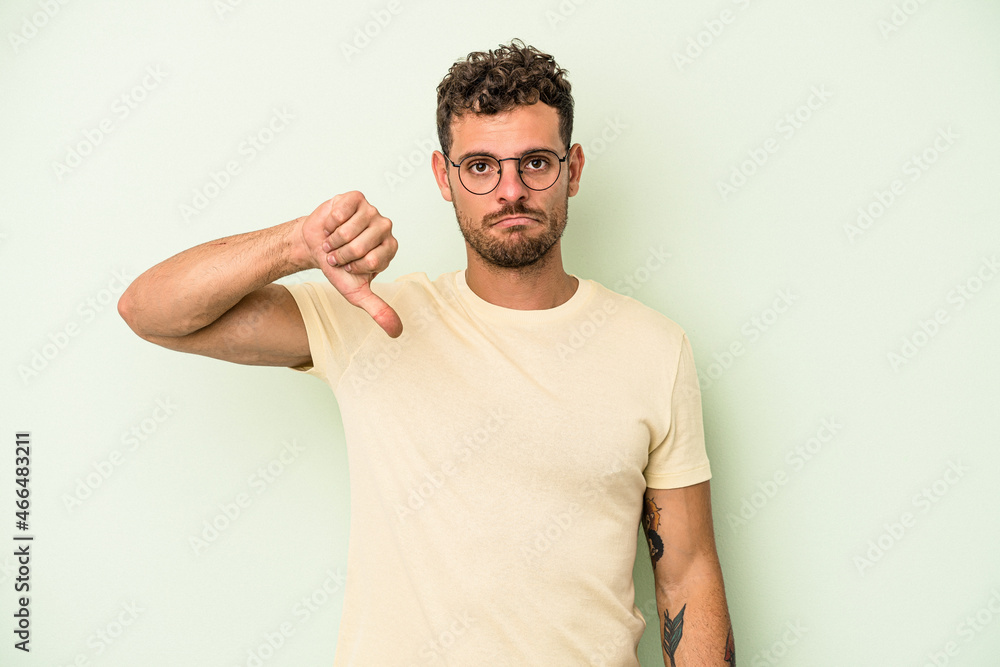 Young caucasian man isolated on green background showing a dislike gesture, thumbs down. Disagreement concept. Young caucasian man isolated on green background showing a dislike gesture, thumbs down. Disagreement concept.