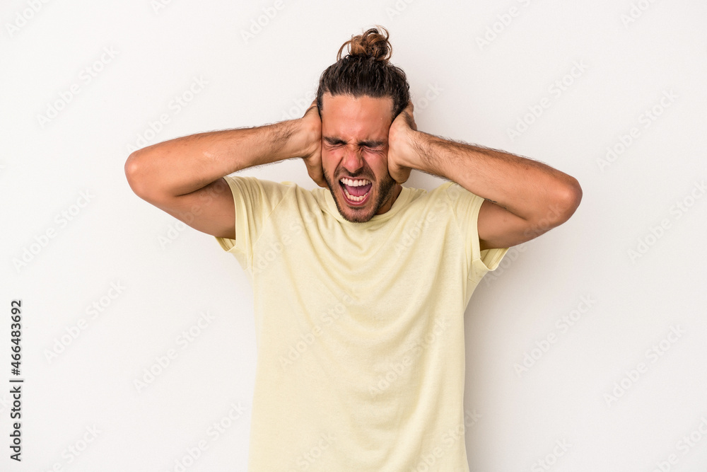 Young caucasian man isolated on white background covering ears with hands trying not to hear too loud sound. Young caucasian man isolated on white background covering ears with hands trying not to hear too loud sound.