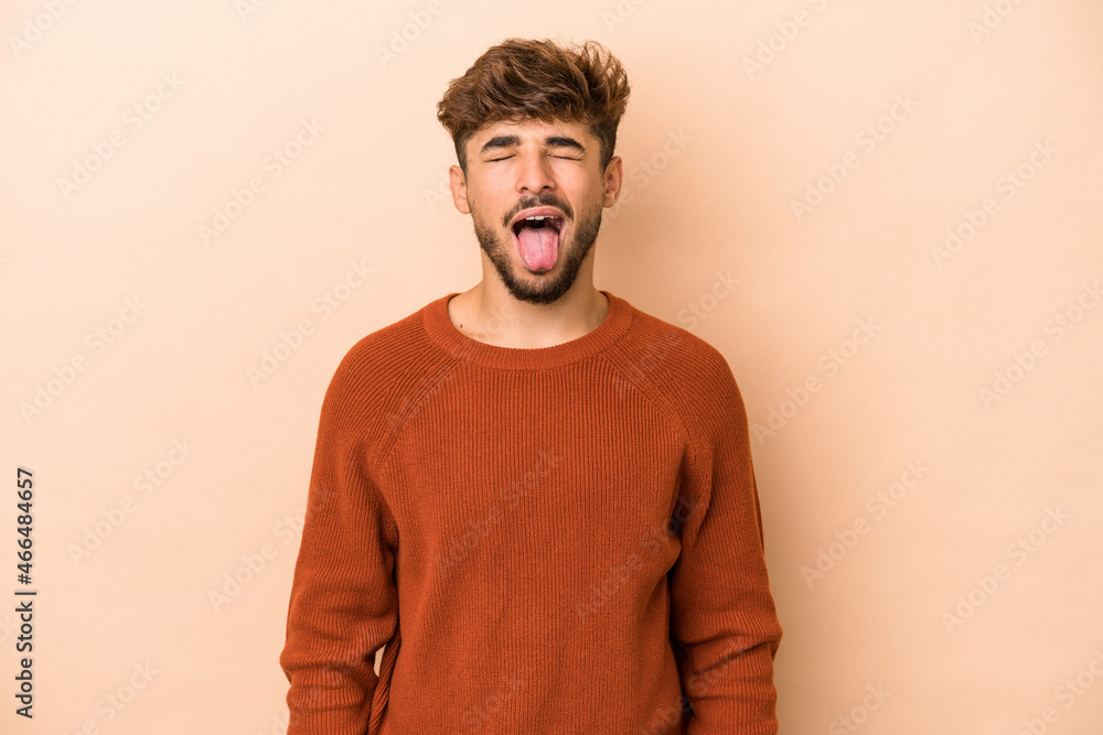 Young arab man isolated on beige background funny and friendly sticking out tongue. Young arab man isolated on beige background funny and friendly sticking out tongue.